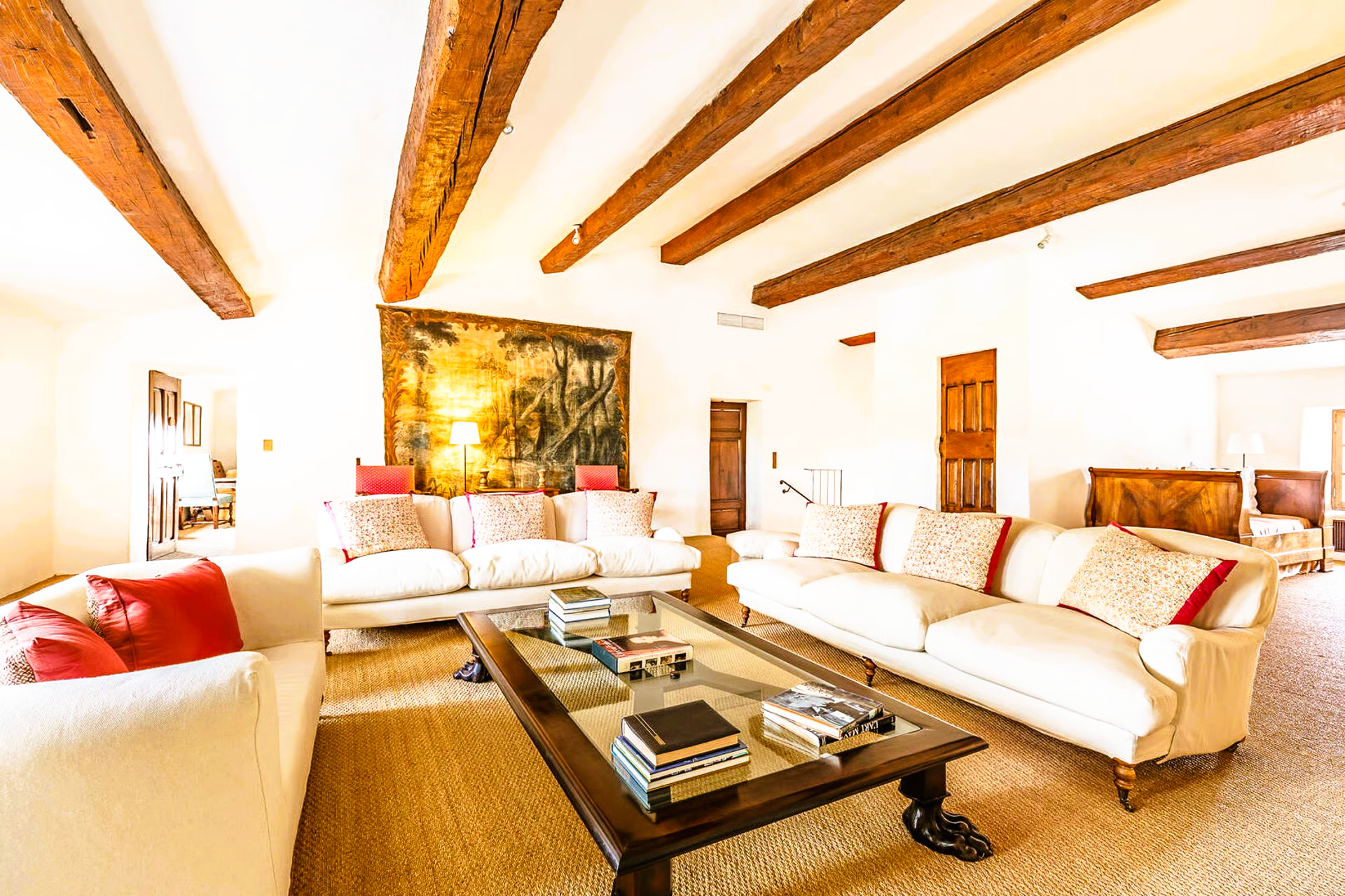 Bright living room with white couches, wood beams, and a coffee table.