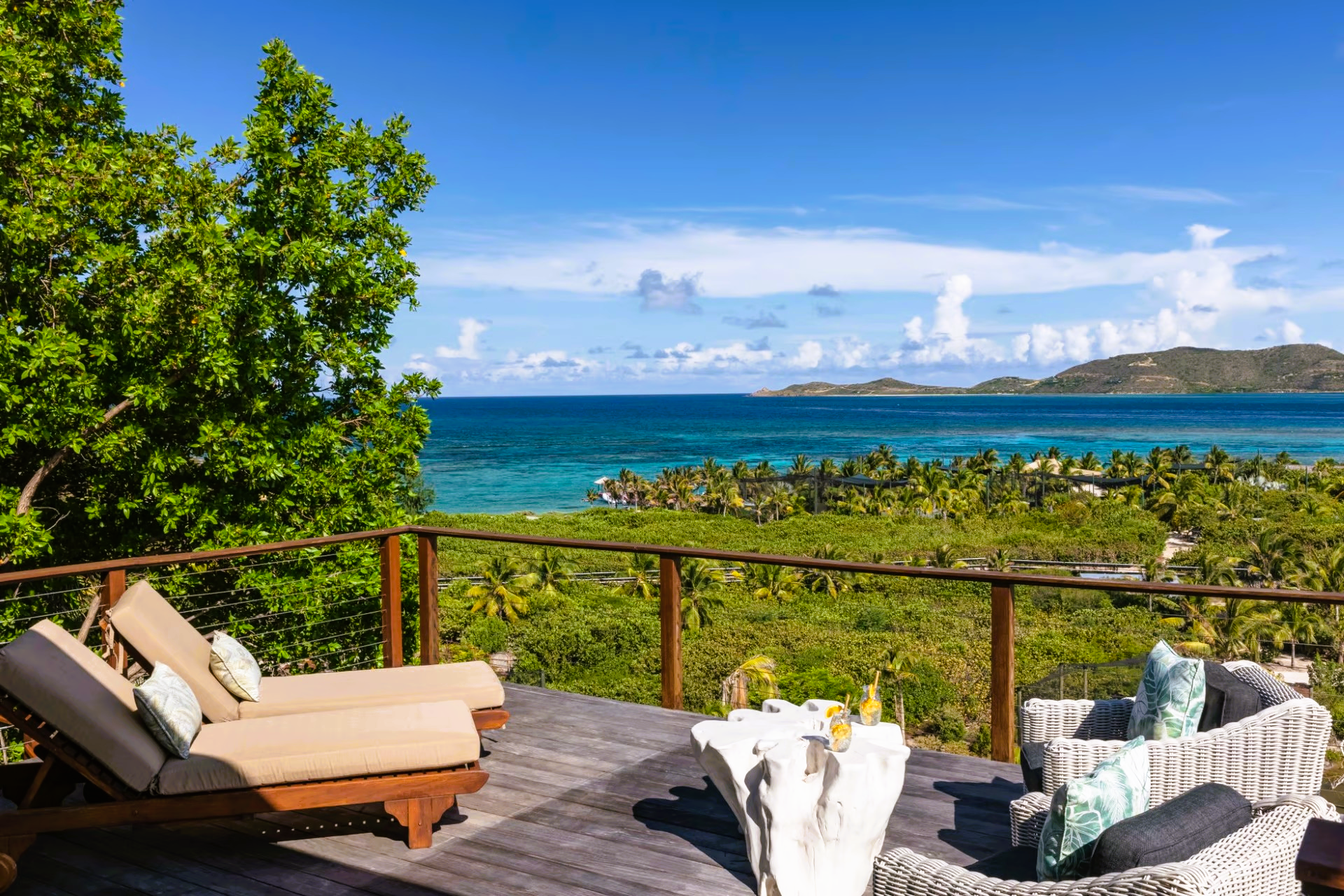 A deck with chairs and a table overlooking the ocean.