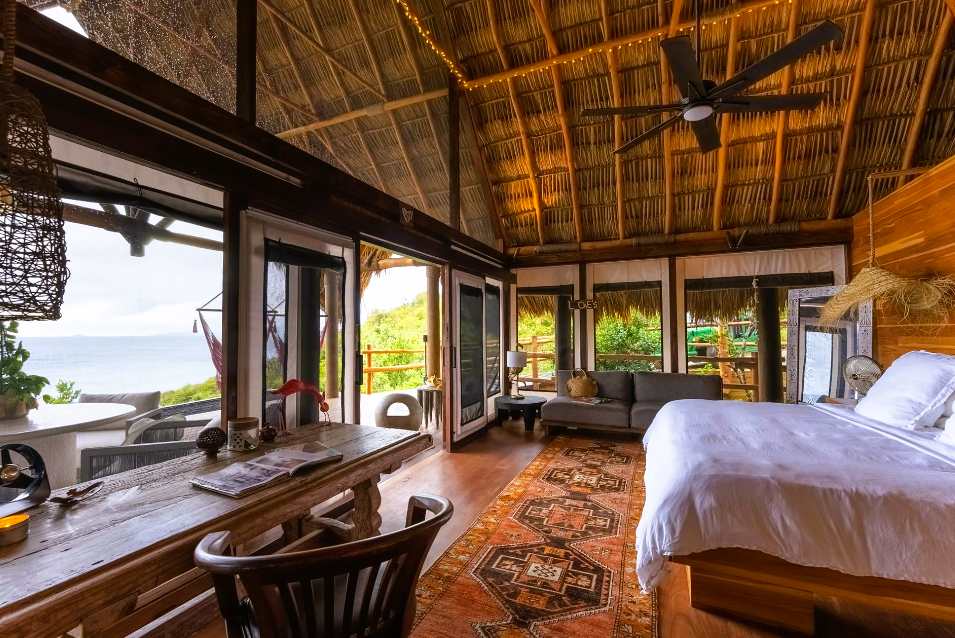 There is a large bed in the middle of the room with a ceiling fan.