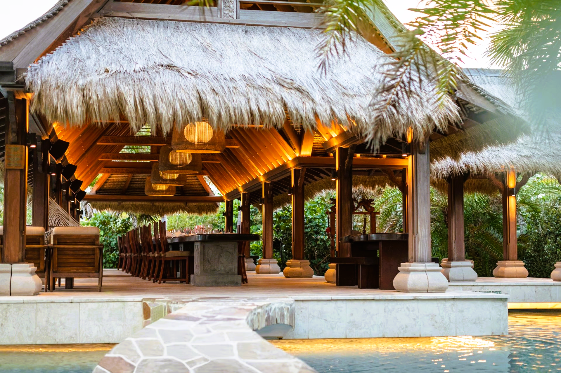 A thatched hut with a swimming pool in front of it