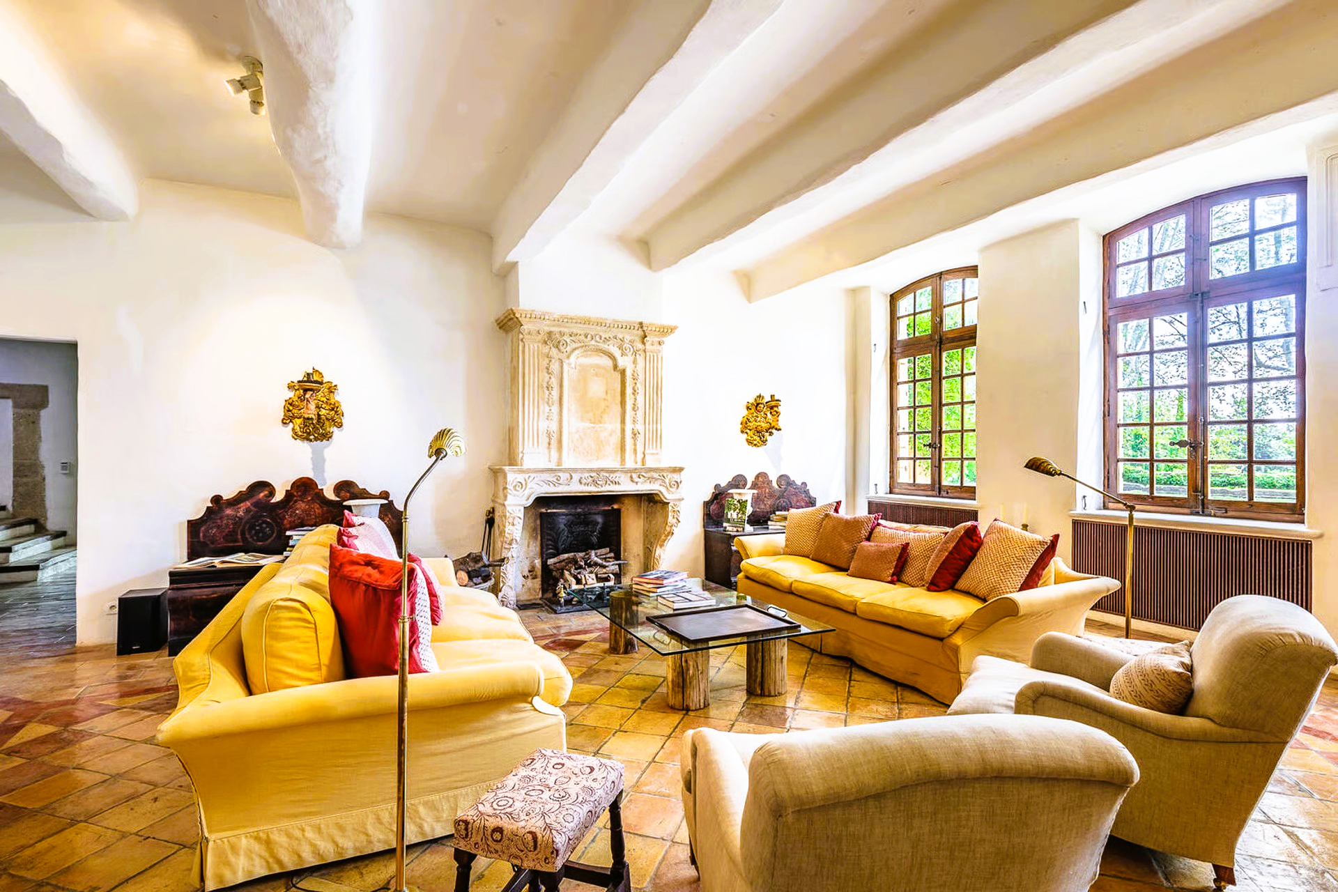 Living room with yellow couches, a fireplace, and large windows.