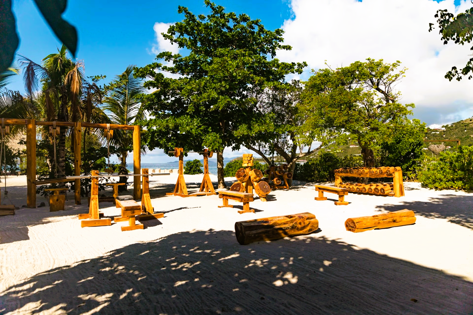 A wooden playground on a beach with trees in the background