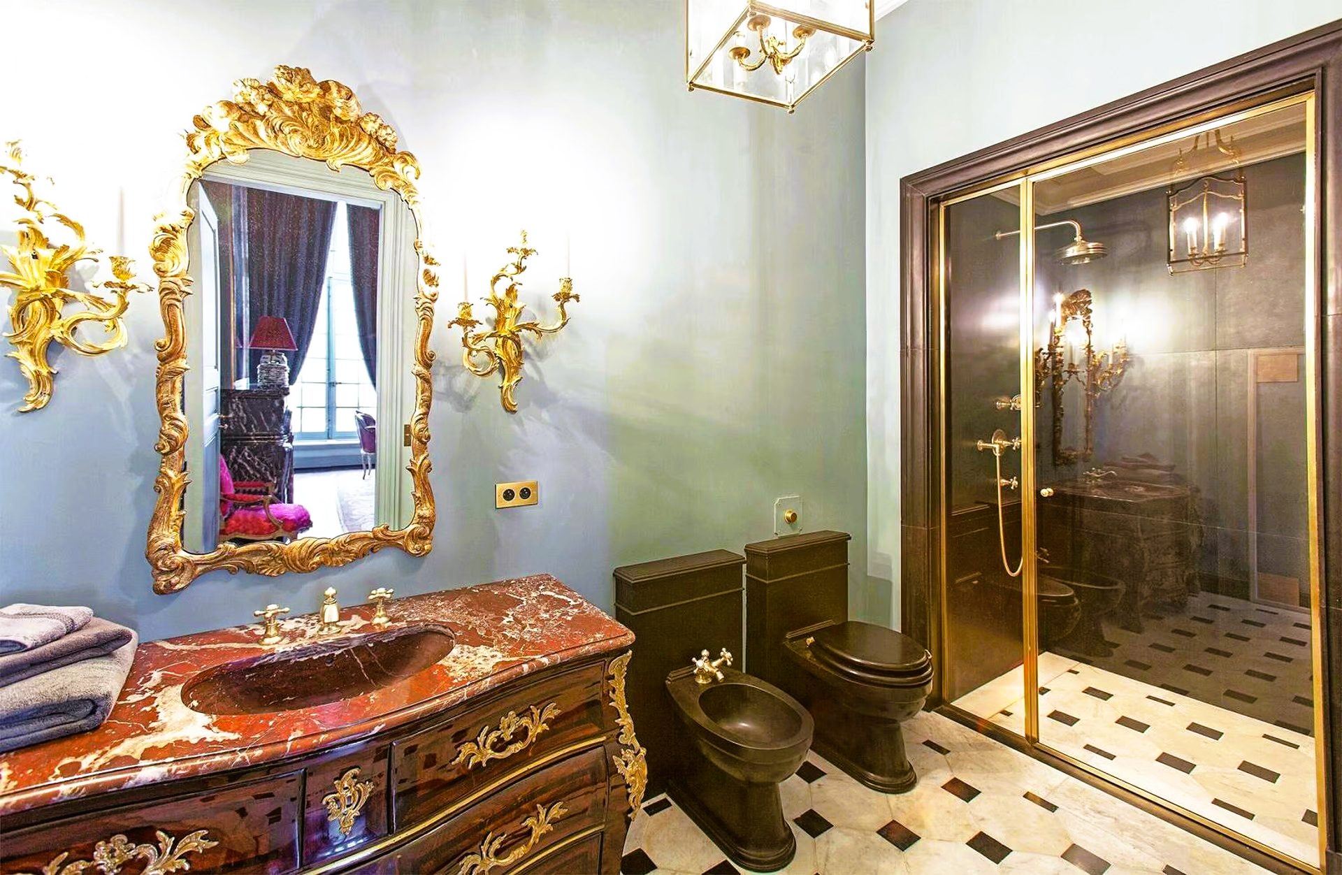 A bathroom with two toilets , a sink and a mirror.