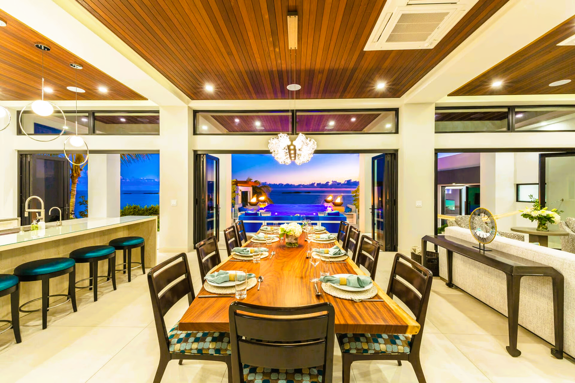 A dining room with a long table and chairs and a view of the ocean.