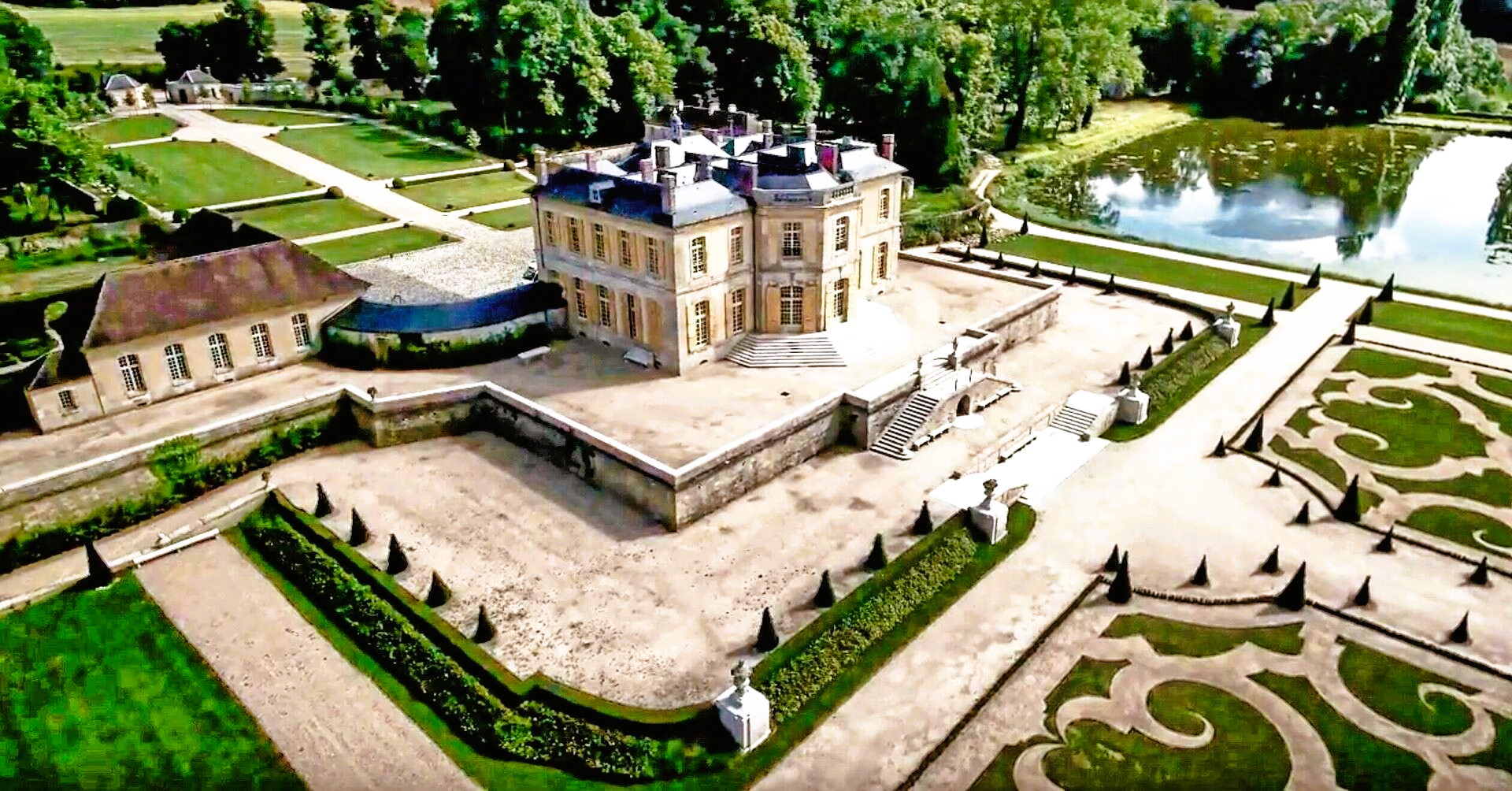 An aerial view of a large castle surrounded by gardens and trees.