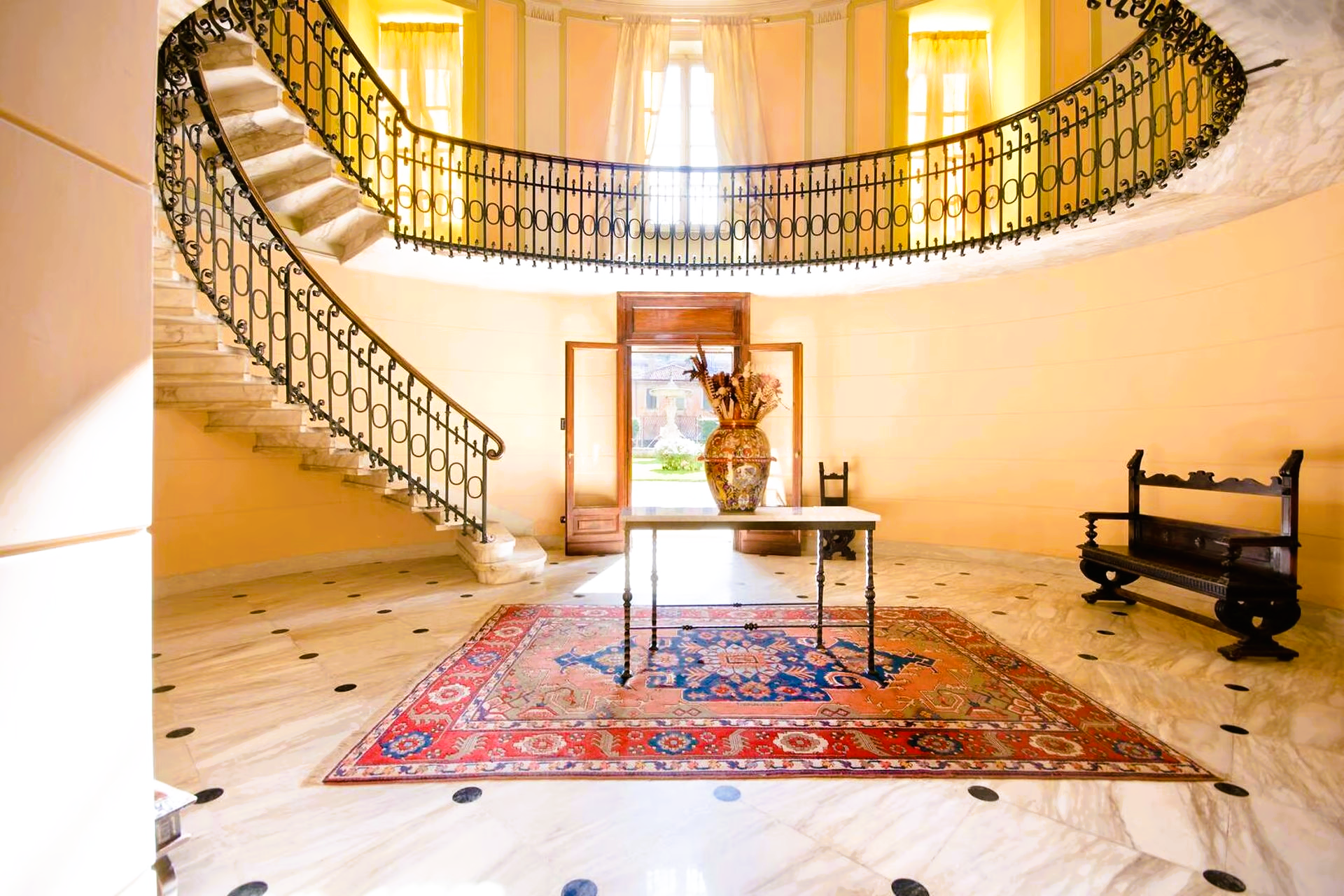 A large hallway with a spiral staircase and a rug on the floor.