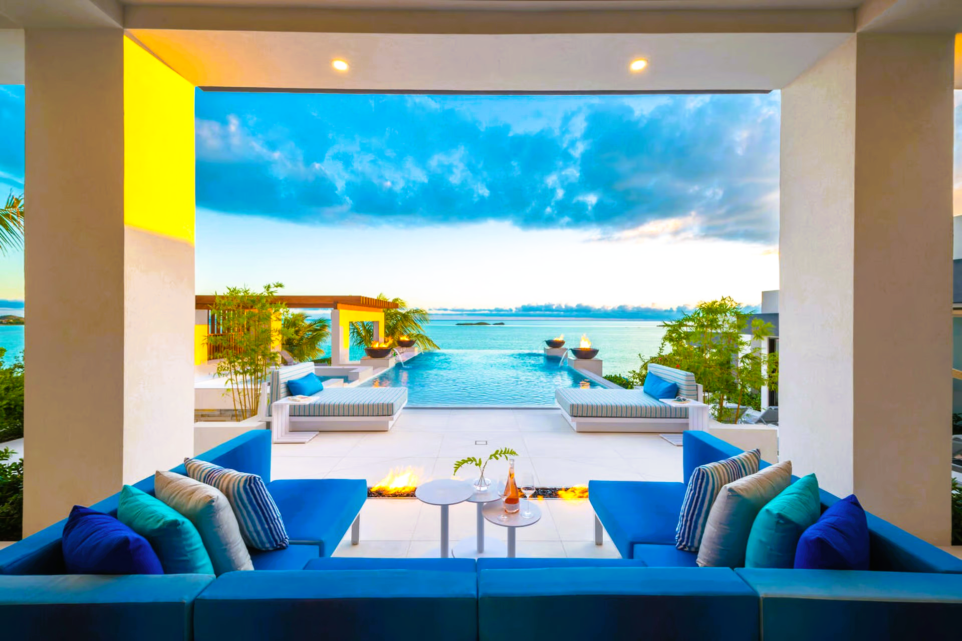A living room with blue couches and a swimming pool in the background