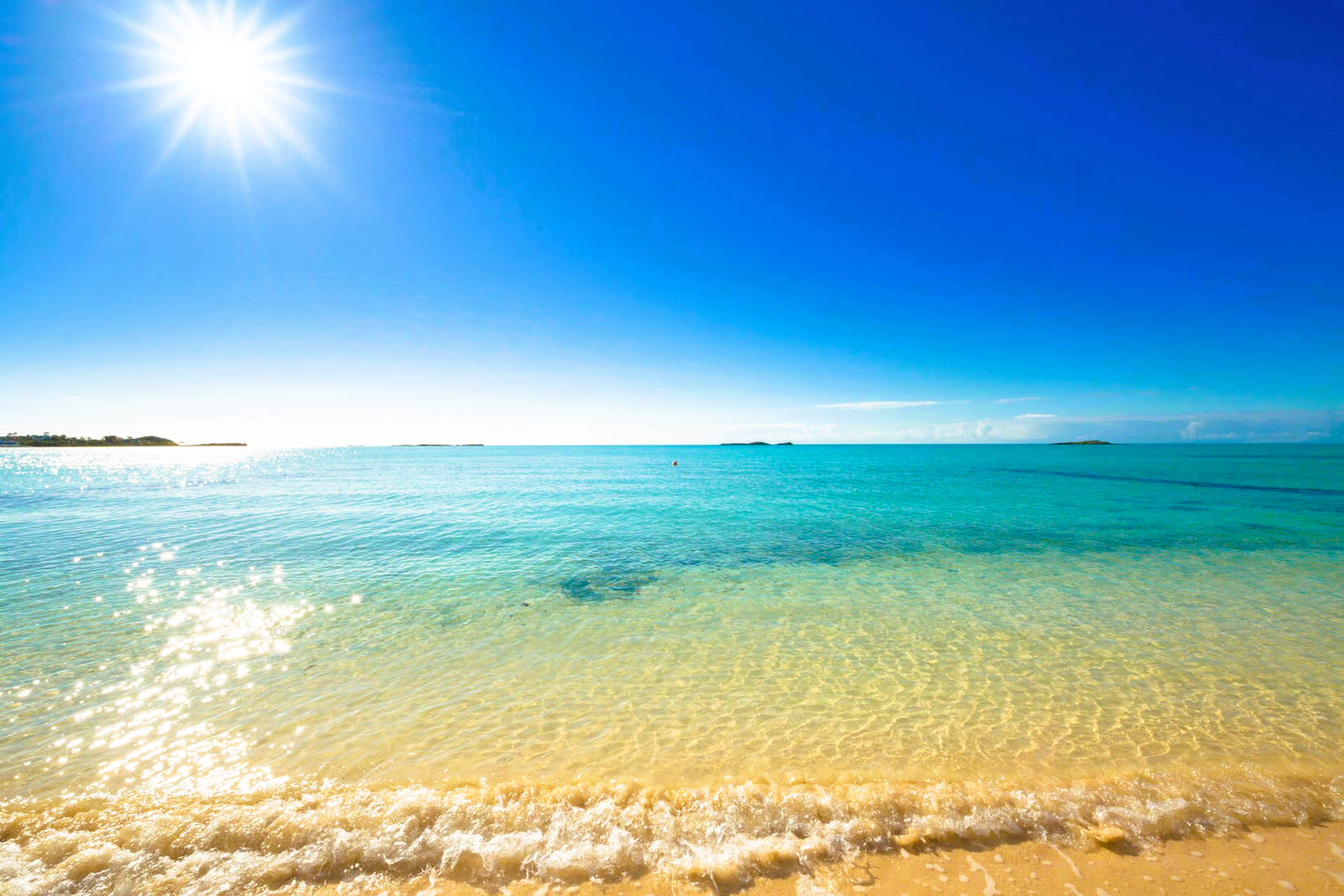 The sun is shining brightly on the beach and the ocean.