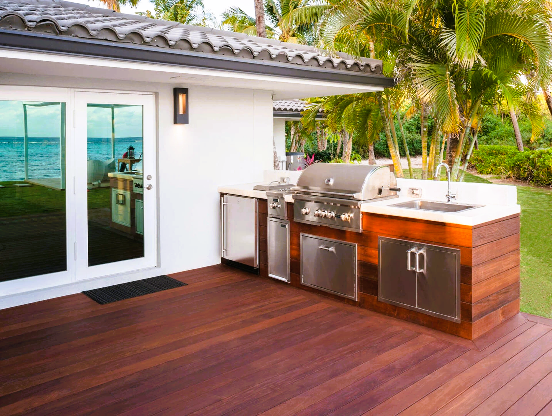 An outdoor kitchen with a grill and sink on a wooden deck