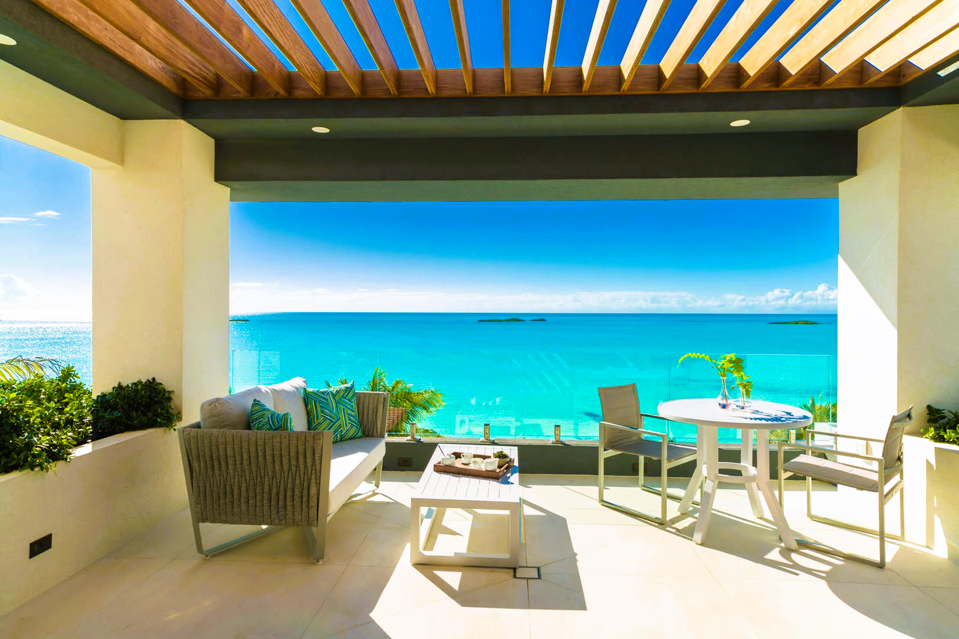 A balcony with a view of the ocean and a table and chairs.