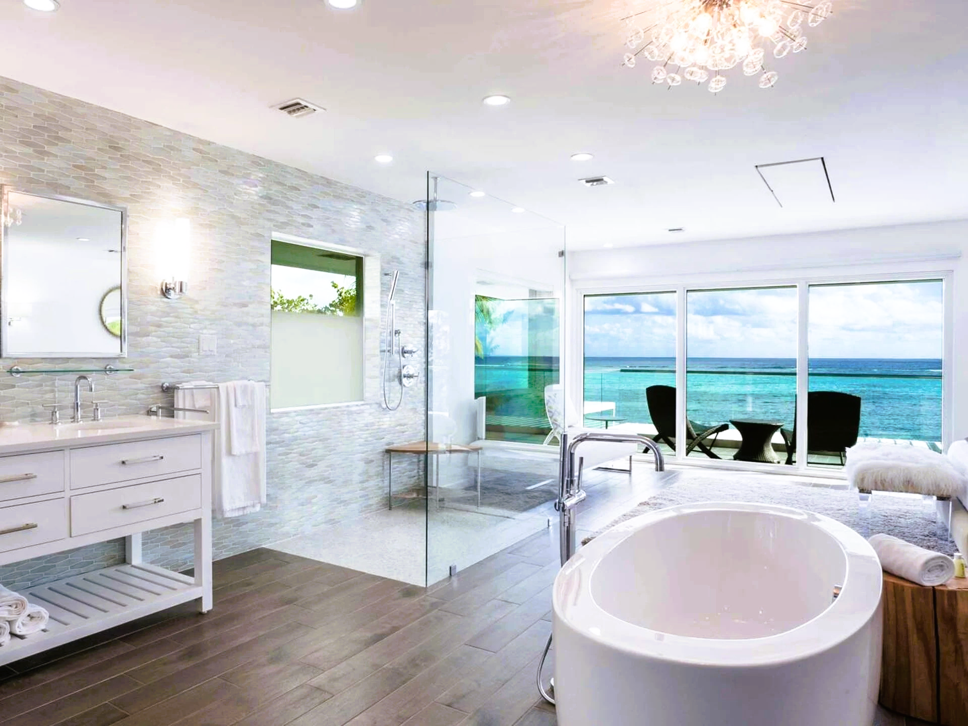 A bathroom with a bathtub , sink , shower and a view of the ocean.