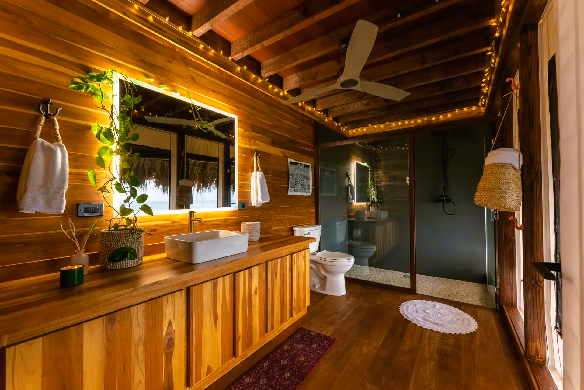 A bathroom with a toilet , sink , mirror and ceiling fan.