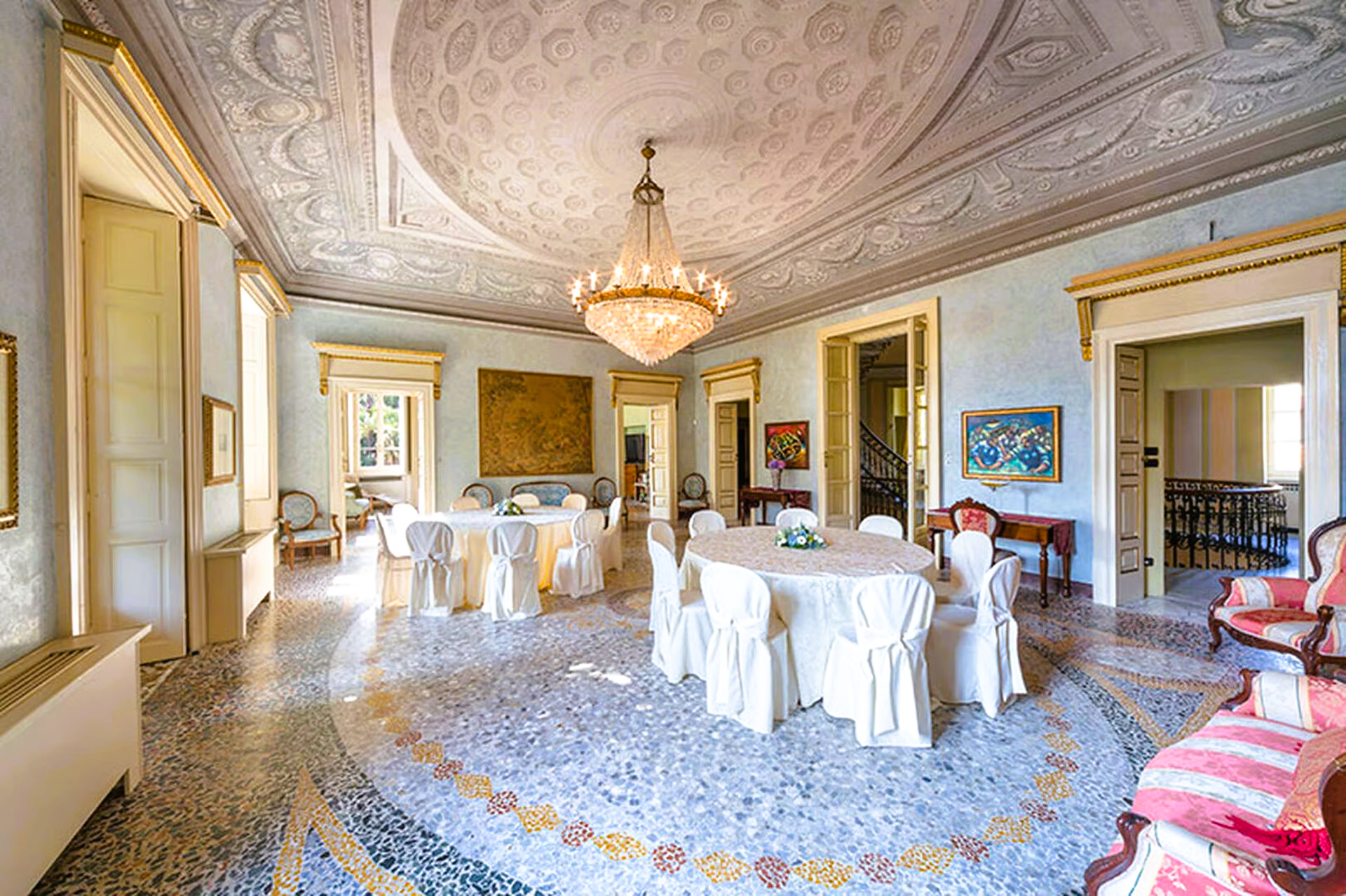 A large room with a table and chairs and a chandelier hanging from the ceiling.