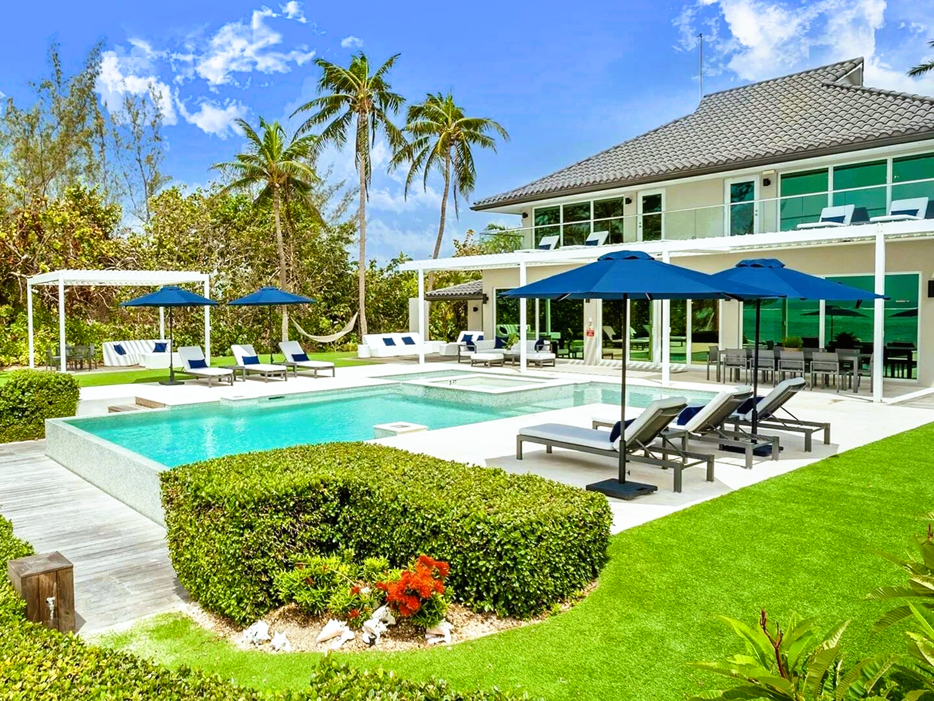 A large house with a swimming pool and umbrellas in front of it