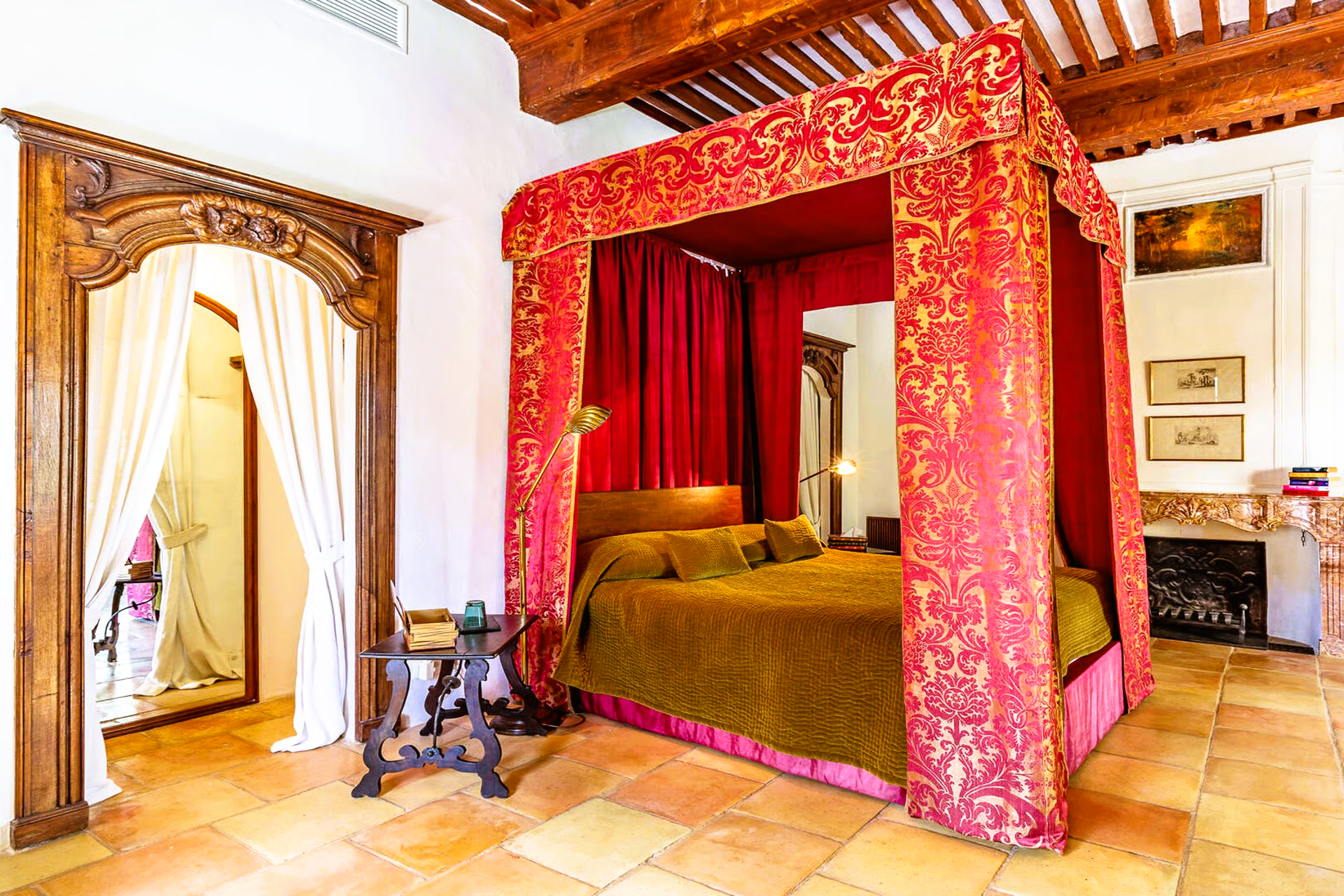 Bedroom with red canopy bed, wooden accents, and a doorway with curtains.