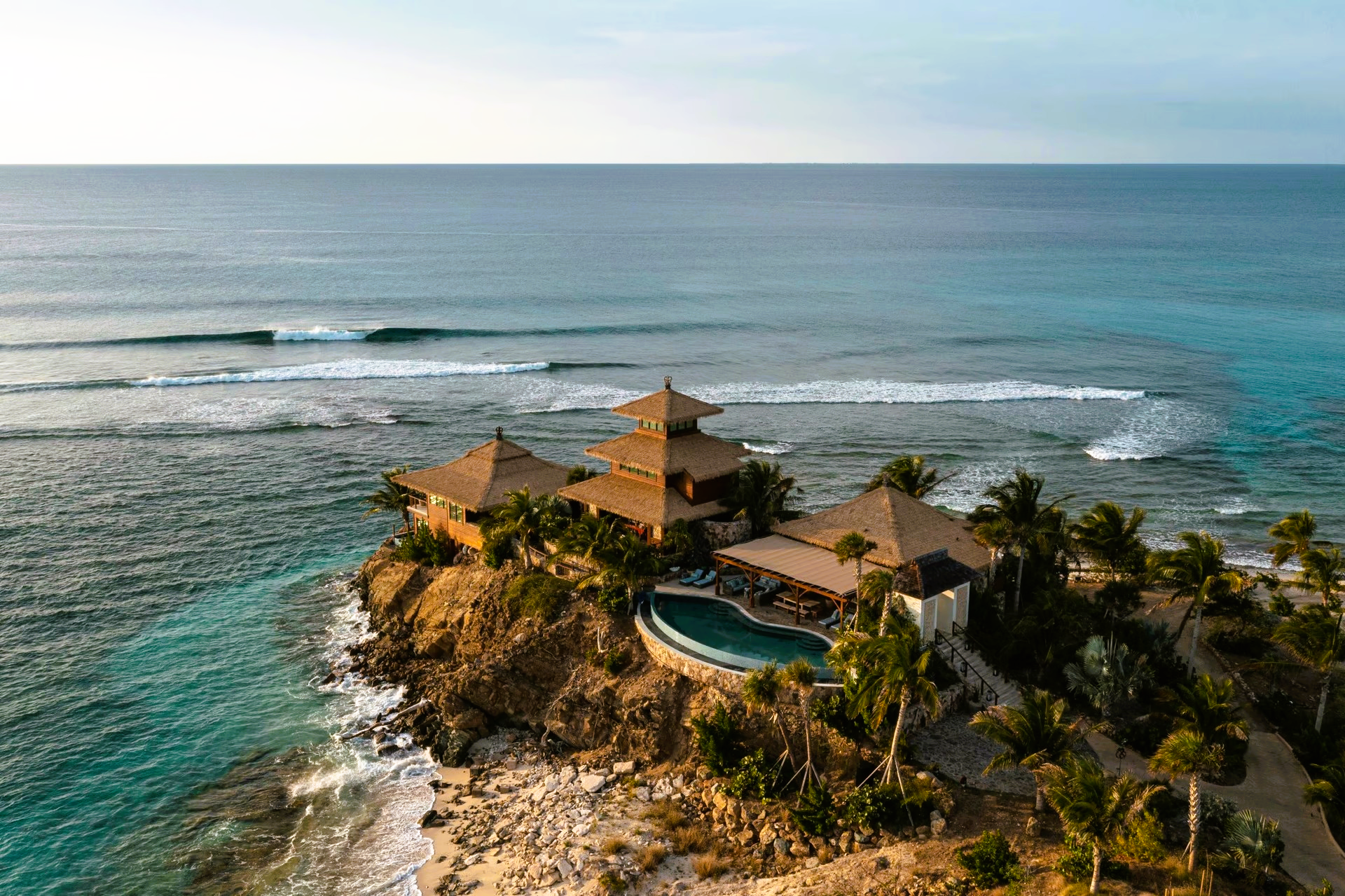 An aerial view of a house on a small island in the middle of the ocean.