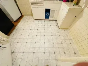 White kitchen with tiled floor, cabinets, and appliances.