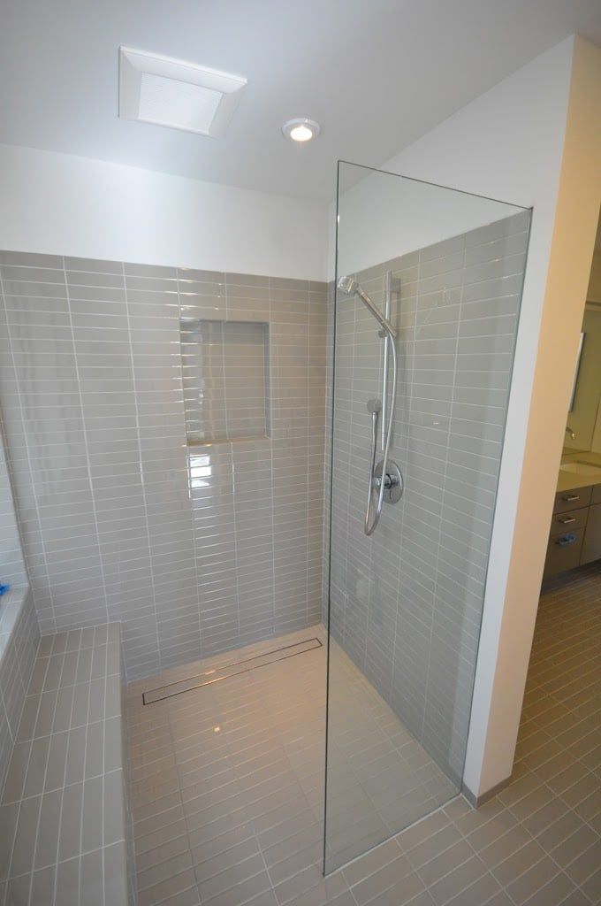 A walk in shower with a glass door in a bathroom.