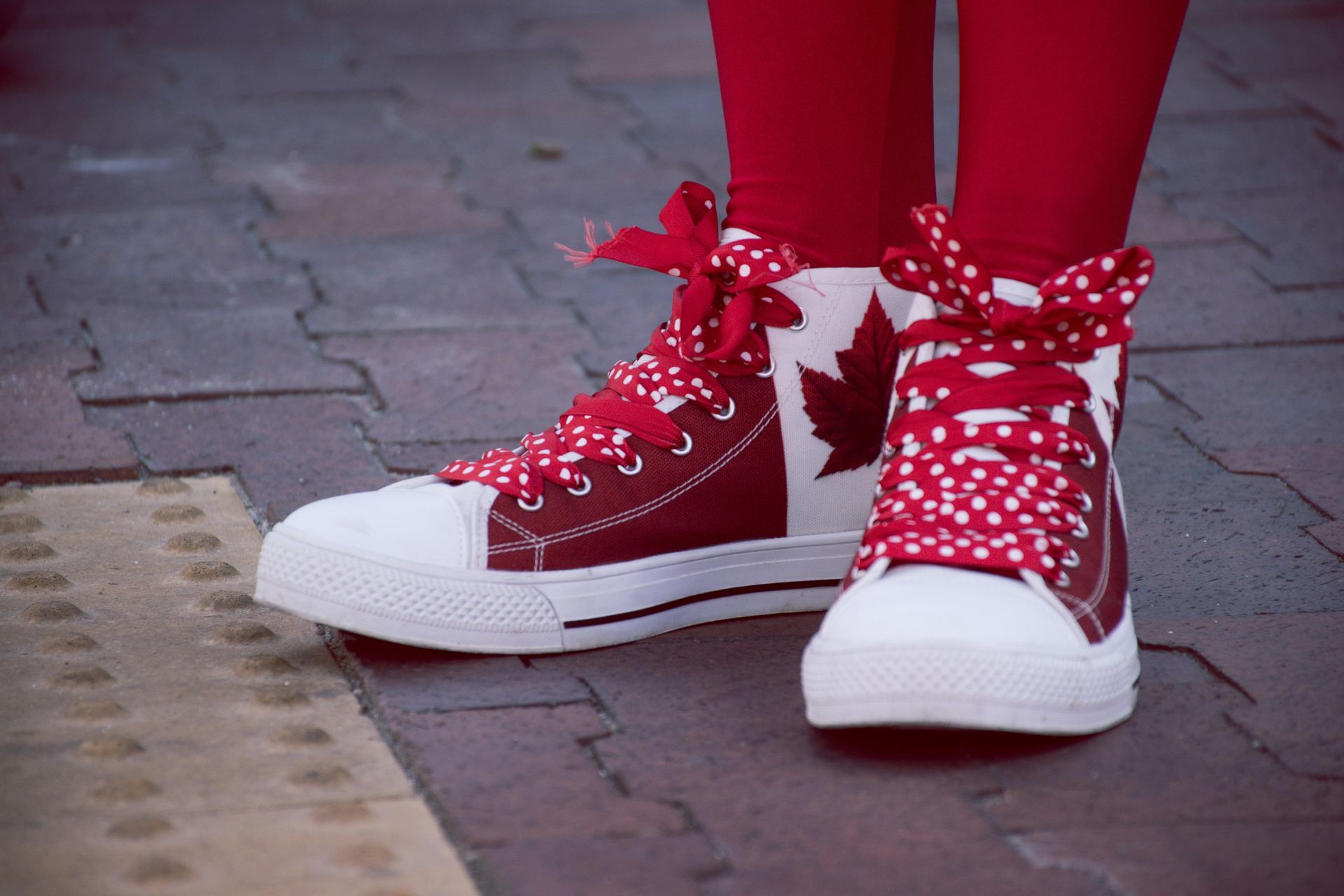 A person wearing red and white sneakers with a maple leaf on them