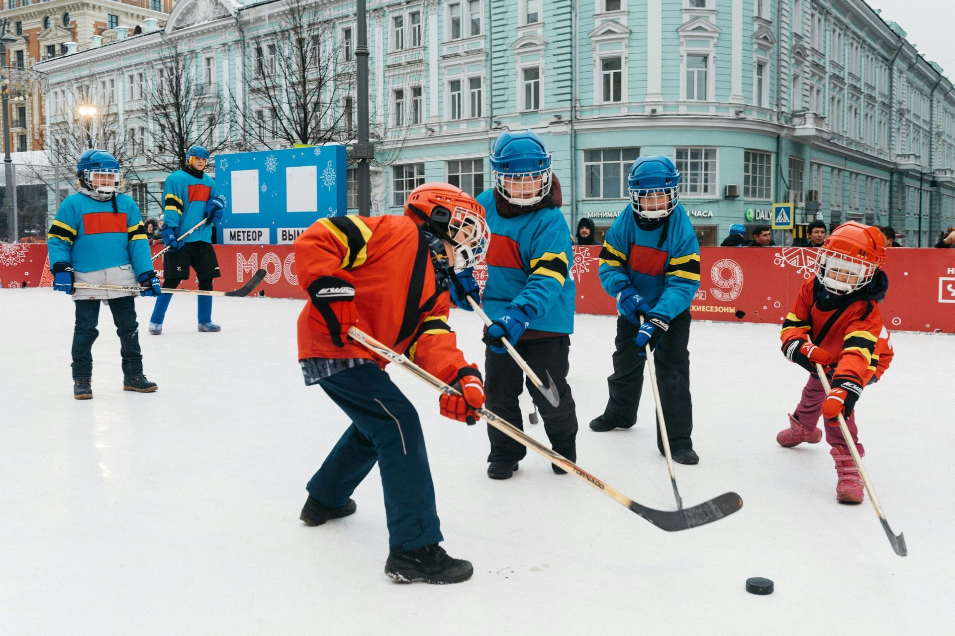 A group of children are playing ice hockey on a rink.