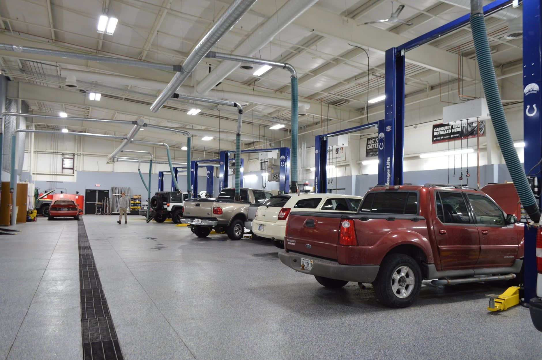 A row of trucks are parked in a large garage | Full Throttle Automotive Llc