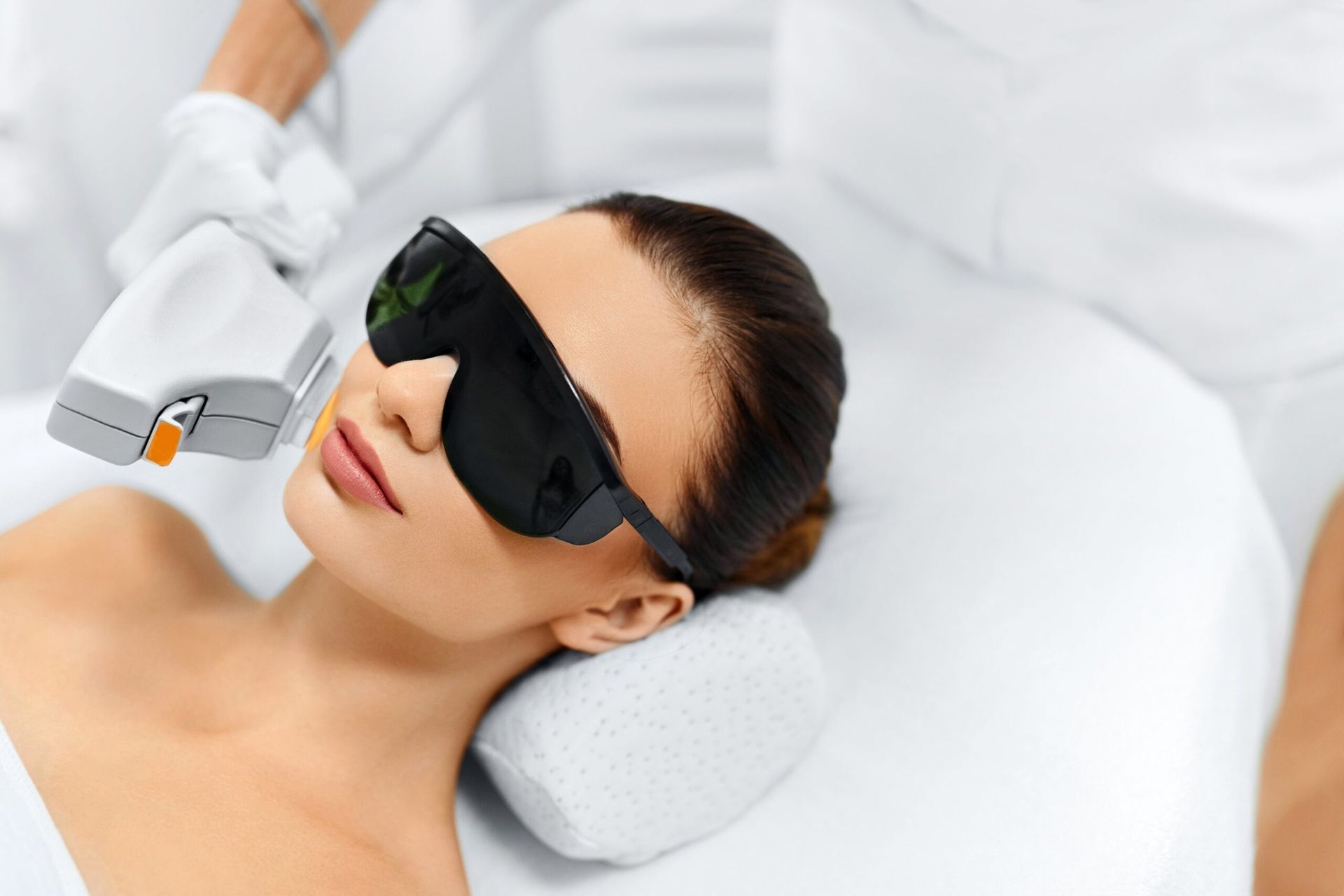 A woman is getting a laser hair removal treatment on her face.