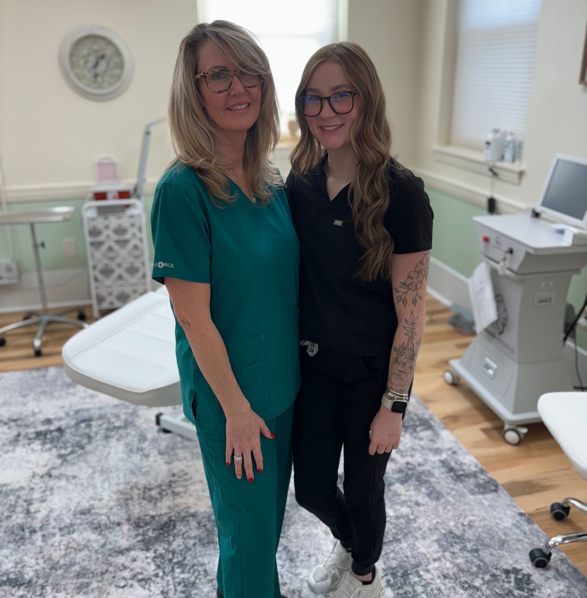 Two women in scrubs are posing for a picture in a room