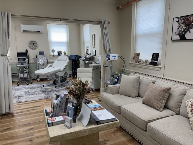 Salon interior with aesthetic equipment, a couch, and a treatment bed.