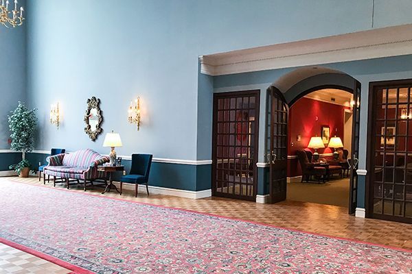 Hallway with blue walls, red carpet, and arched doorway leading to a red-walled room.