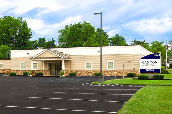 Cannon Funeral Home sign in front of beige and brown building. Blue sign with white text.