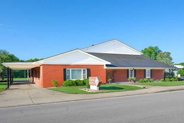 Brick funeral home with green lawn, blue sky, and sign.