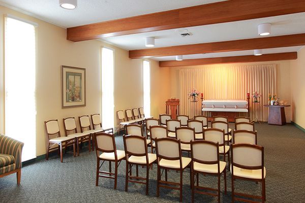 Funeral home chapel with seating facing a casket, neutral colors.
