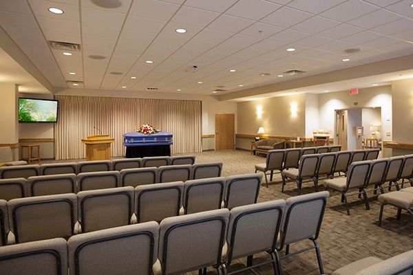 Funeral home chapel with rows of seating facing a casket covered with a blue cloth.