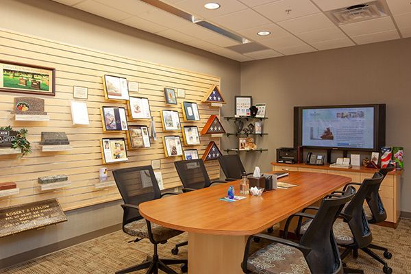 Conference room with wooden table and chairs, displaying framed photos and a television screen.
