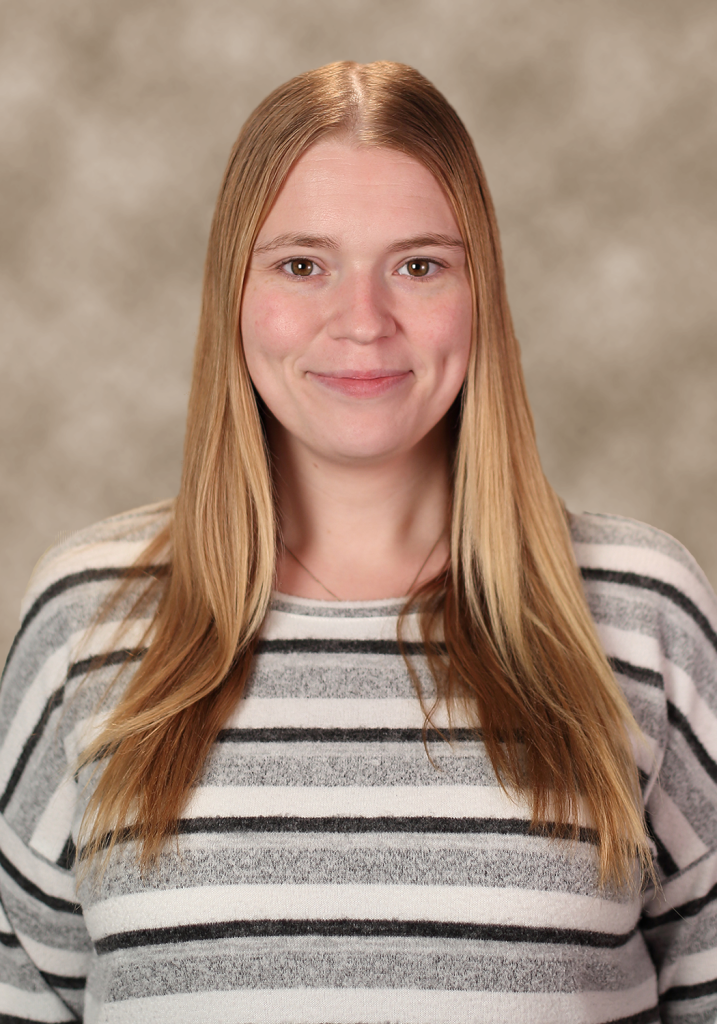 Woman with long blonde hair wearing a striped sweater, smiling at the camera.