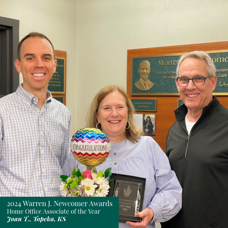 Three people celebrating. Woman holding an award and balloon, flanked by two men, smiling in an office setting. Text: