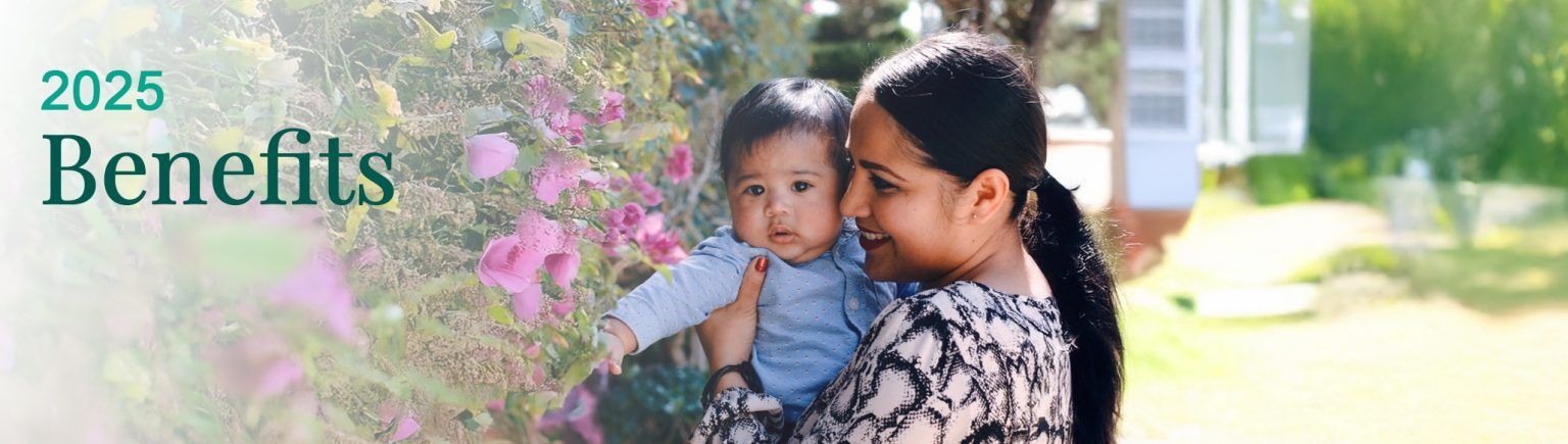 Woman holds a baby near pink flowers, with 