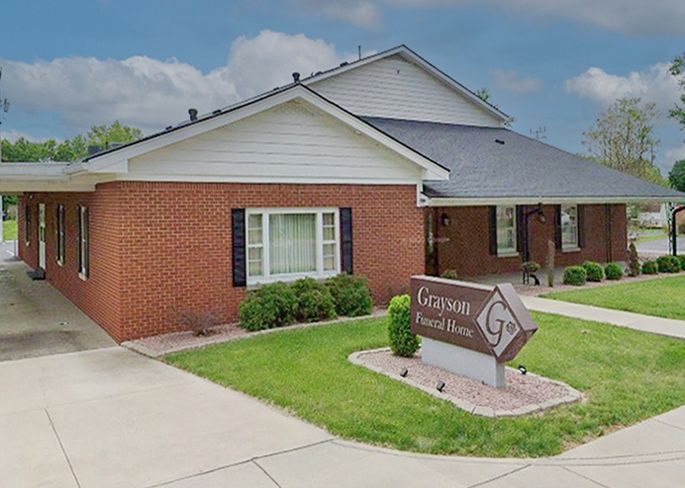 Grayson Funeral Home: Brick building with sign on a lawn, under a cloudy sky.