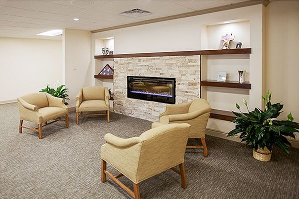 Cozy sitting area with beige chairs, fireplace, and plants.
