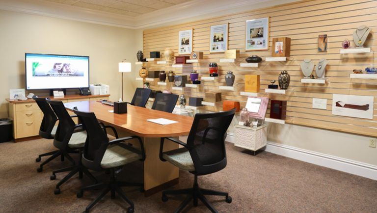 Conference room with a long table, chairs, and displays of urns and jewelry.