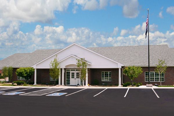 Building with dark brick exterior and flagpole on a clear day. Handicap parking available.
