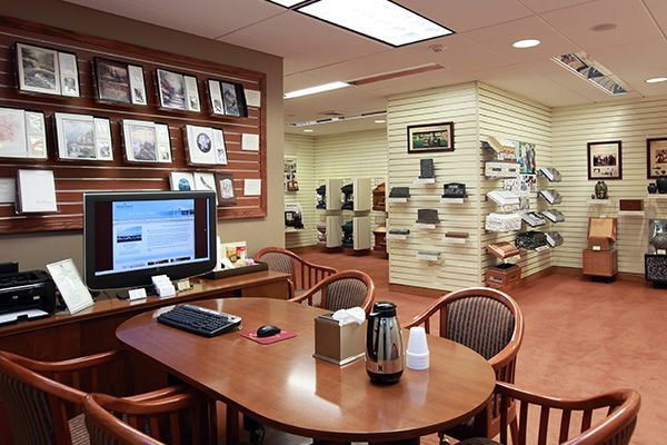 A conference room with a table, chairs, computer, and display of hats and photos.