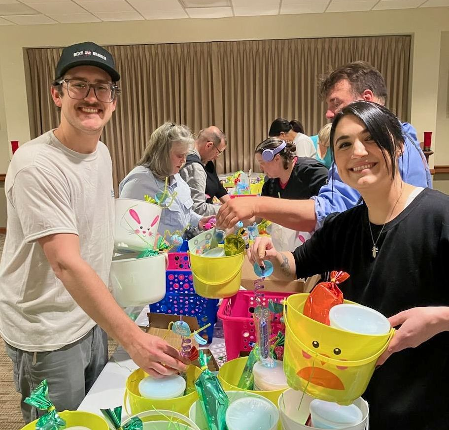 Five smiling people holding ice cream containers; office setting.
