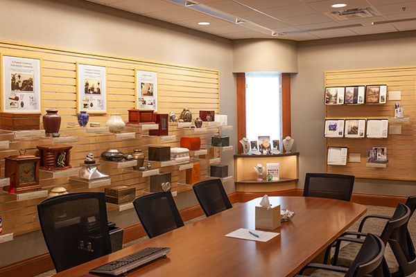A conference room with a table and chairs, display of urns and memorials on the walls.