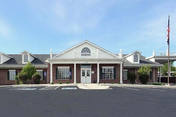 Bank building with brick exterior, white trim, and flagpole against a blue sky.