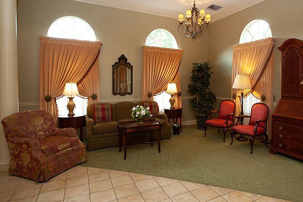 A cozy living room with peach curtains, seating, and a chandelier.