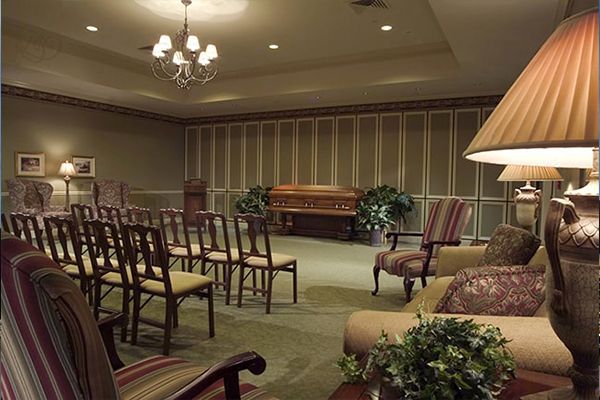Funeral home chapel with chairs, sofa, casket, and floral arrangements.