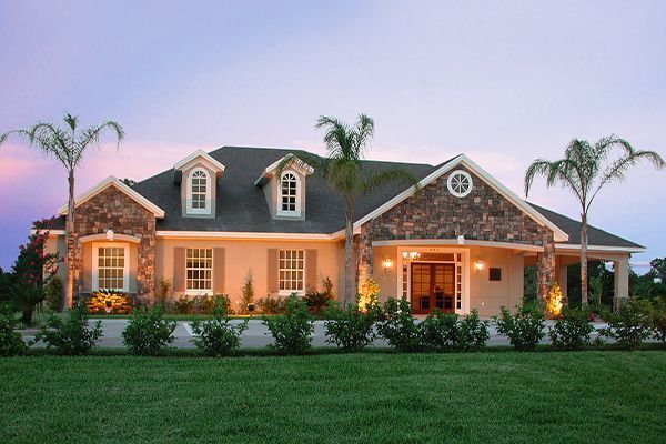 House with stone accents, dormers, and palm trees at dusk.