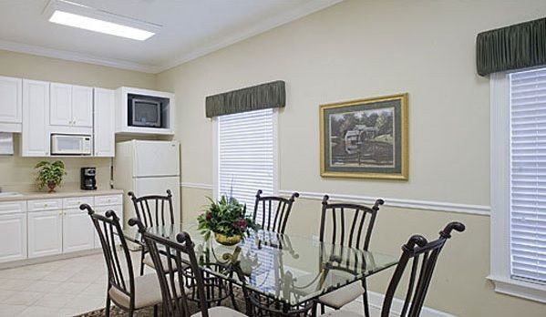 Kitchen and dining area: Glass table with six chairs, white cabinets, and a microwave.