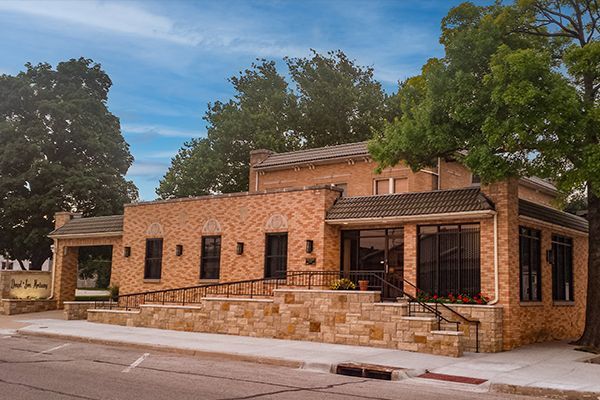 Brick building with a ramp and stairs, trees, and a blue sky.